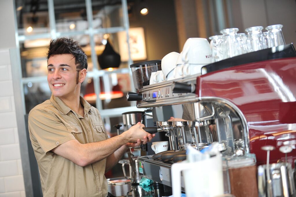 Barista al lavoro dietro il bancone davanti a una macchina professionale per il caff&egrave;
