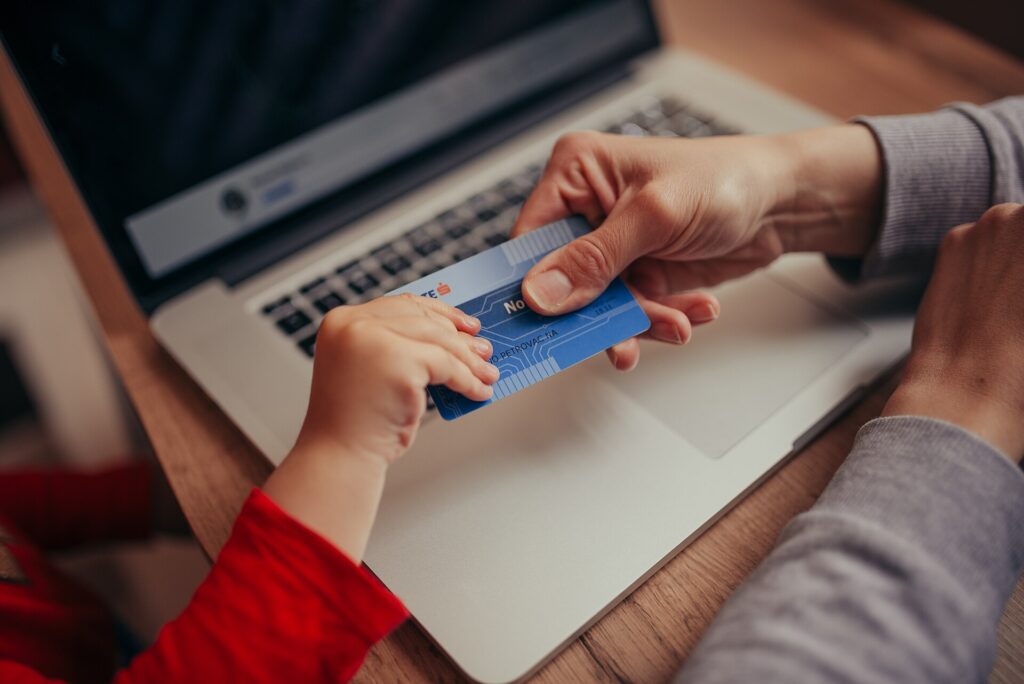 Carta di pagamento appoggiata accanto alla tastiera di un computer portatile acceso