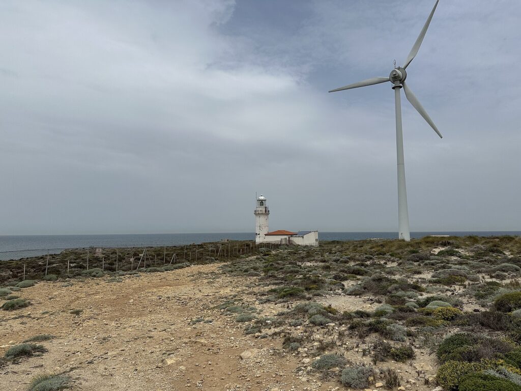 Turbine eoliche allineate in un campo aperto con il cielo coperto sullo sfondo