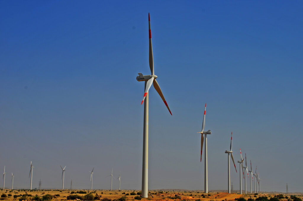 Aerogeneratori allineati sul crinale di una collina con cielo grigio sullo sfondo