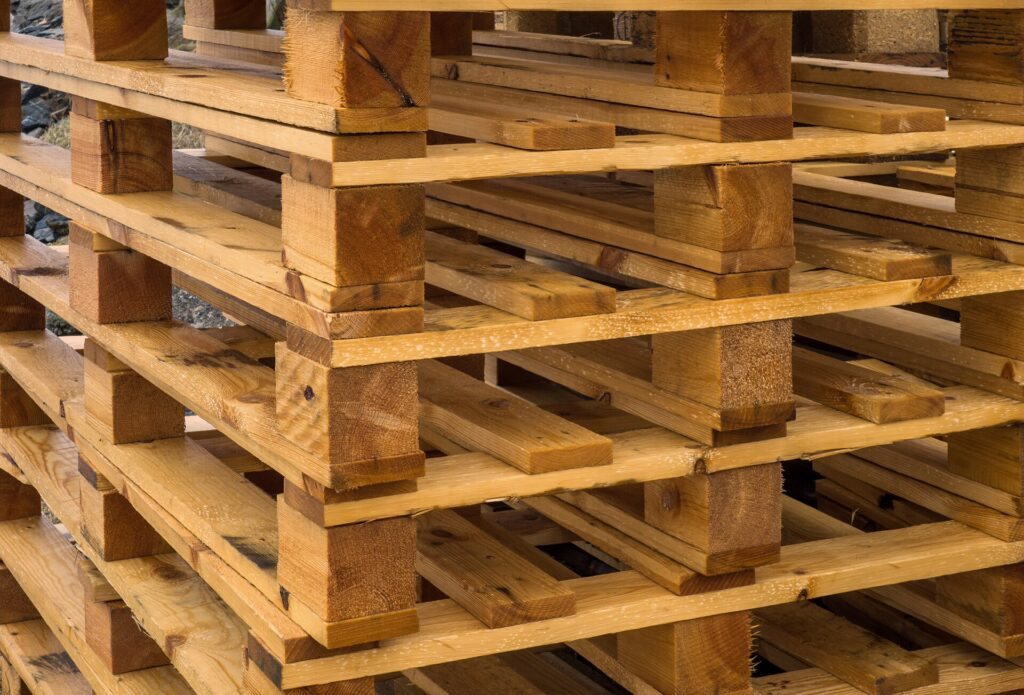Pallet di moduli fotovoltaici impilati e avvolti dentro un magazzino industriale