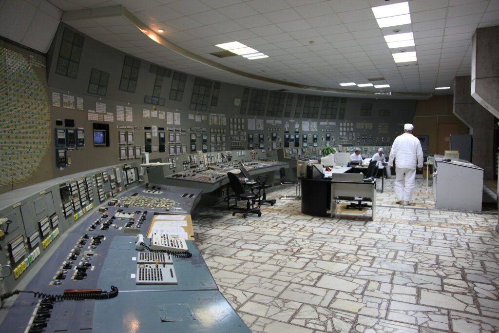 Sala di controllo di una centrale elettrica con pannelli di comando e schermi accesi